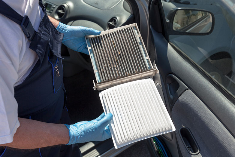 Mechanic replacing dirty car cabin air filter with clean filter