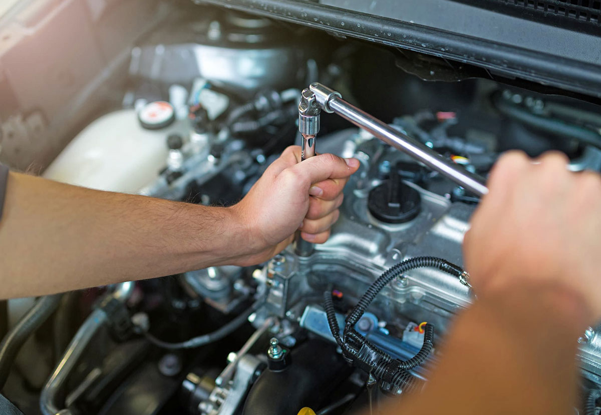 Male mechanic hands fixing the engine of a car