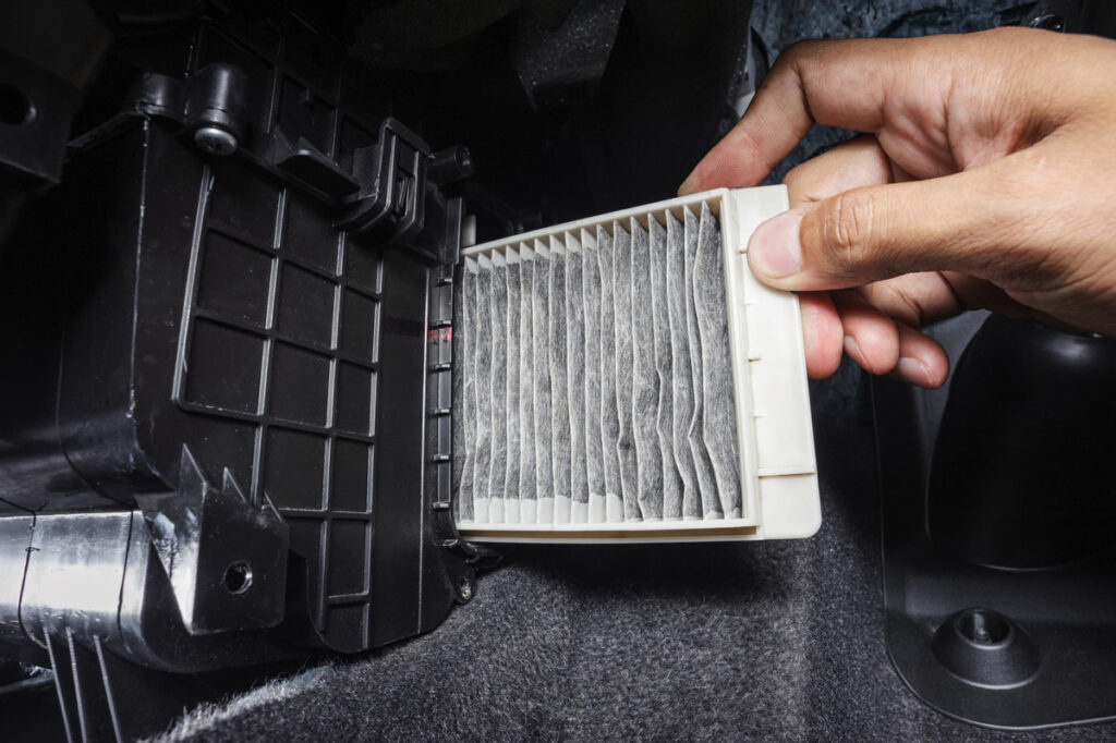 Photo of a hand holding a dirty cabin air filter