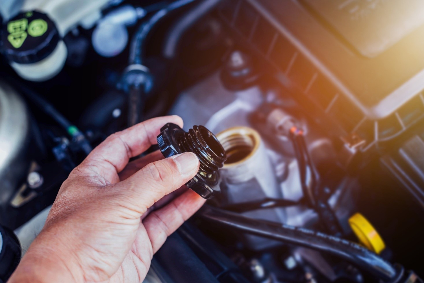 Hand holding a lid of Vehicle engine opened showing up Fluids