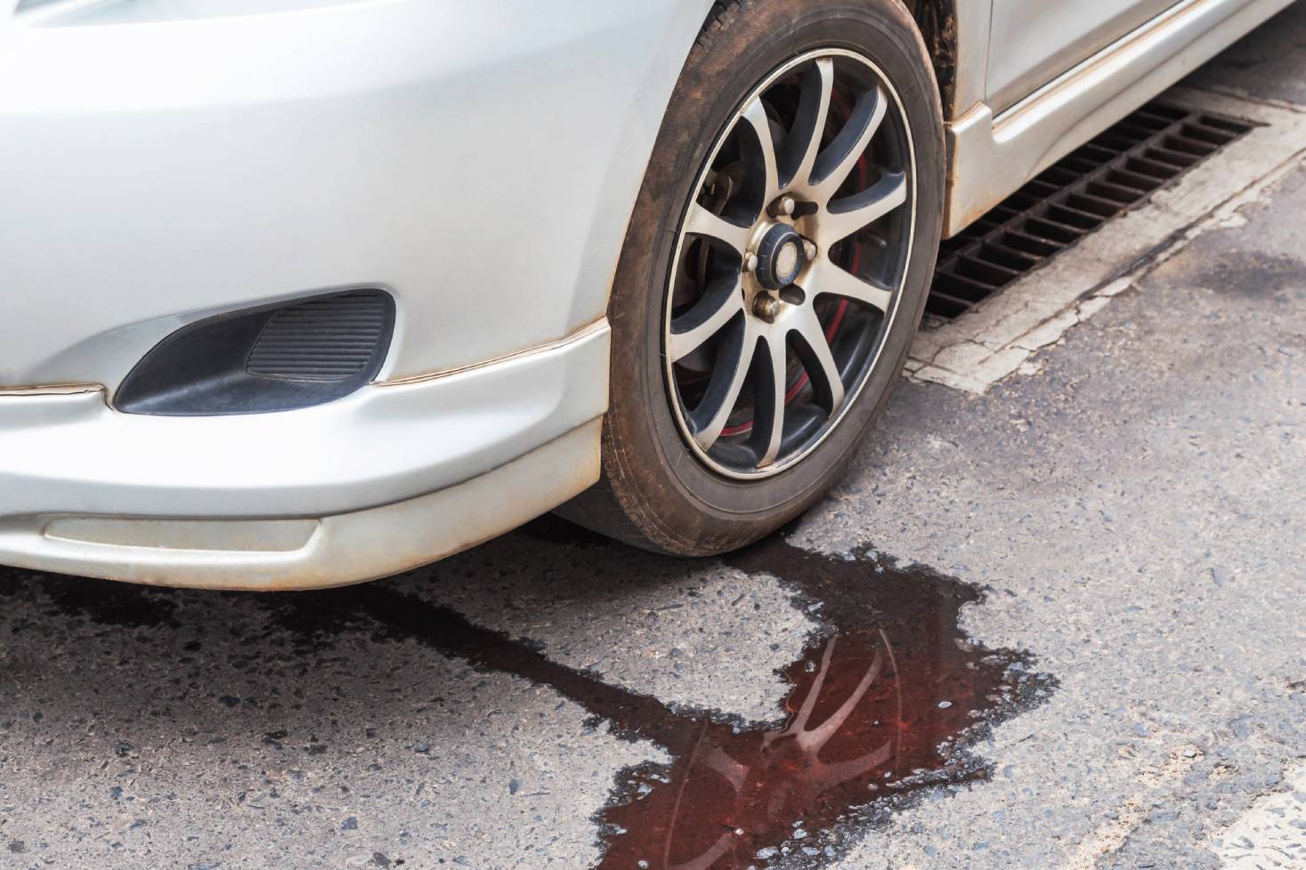 close up of a puddle of oil leaking from a car on the pavement