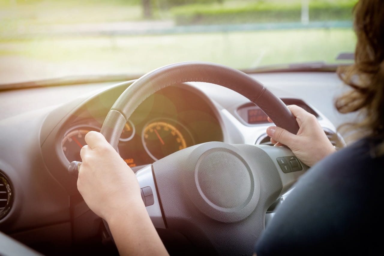 Woman sitting inside car looking at dashboard