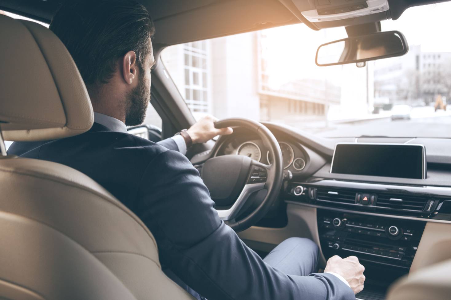Man in business suit with hands on steering wheel