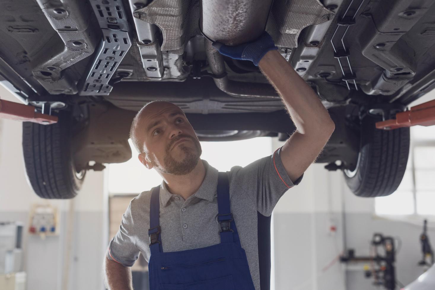 Mechanic inspecting vehicle’s oil pan