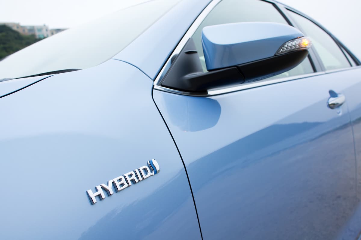 closeup of hybrid vehicle sign on car body